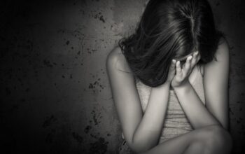 Black and white grunge image of a beautiful teenage girl sitting