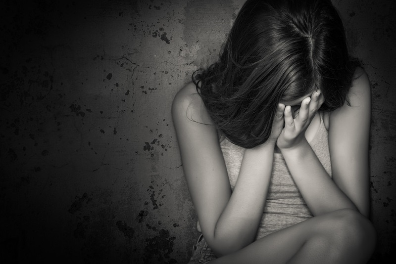 Black and white grunge image of a beautiful teenage girl sitting